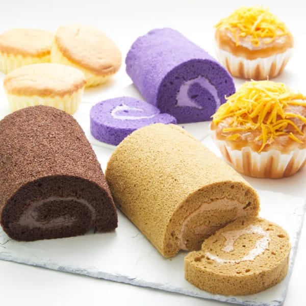 Assortment of Goldilocks Filipino bakery treats: mamon, ube, mocha, and chocolate roll cakes, and ensaymada.